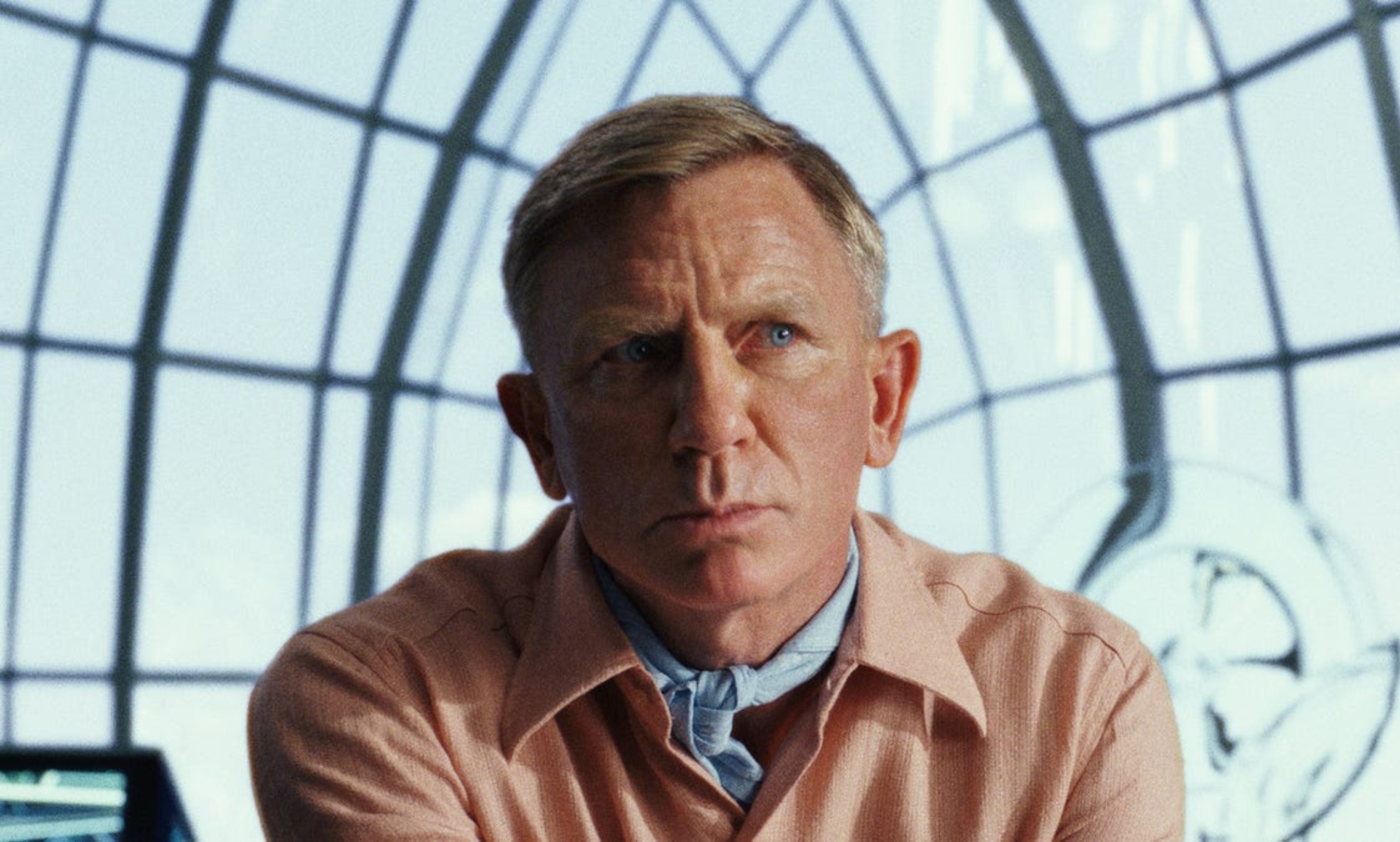 Daniel Craig in a peach suit against a window