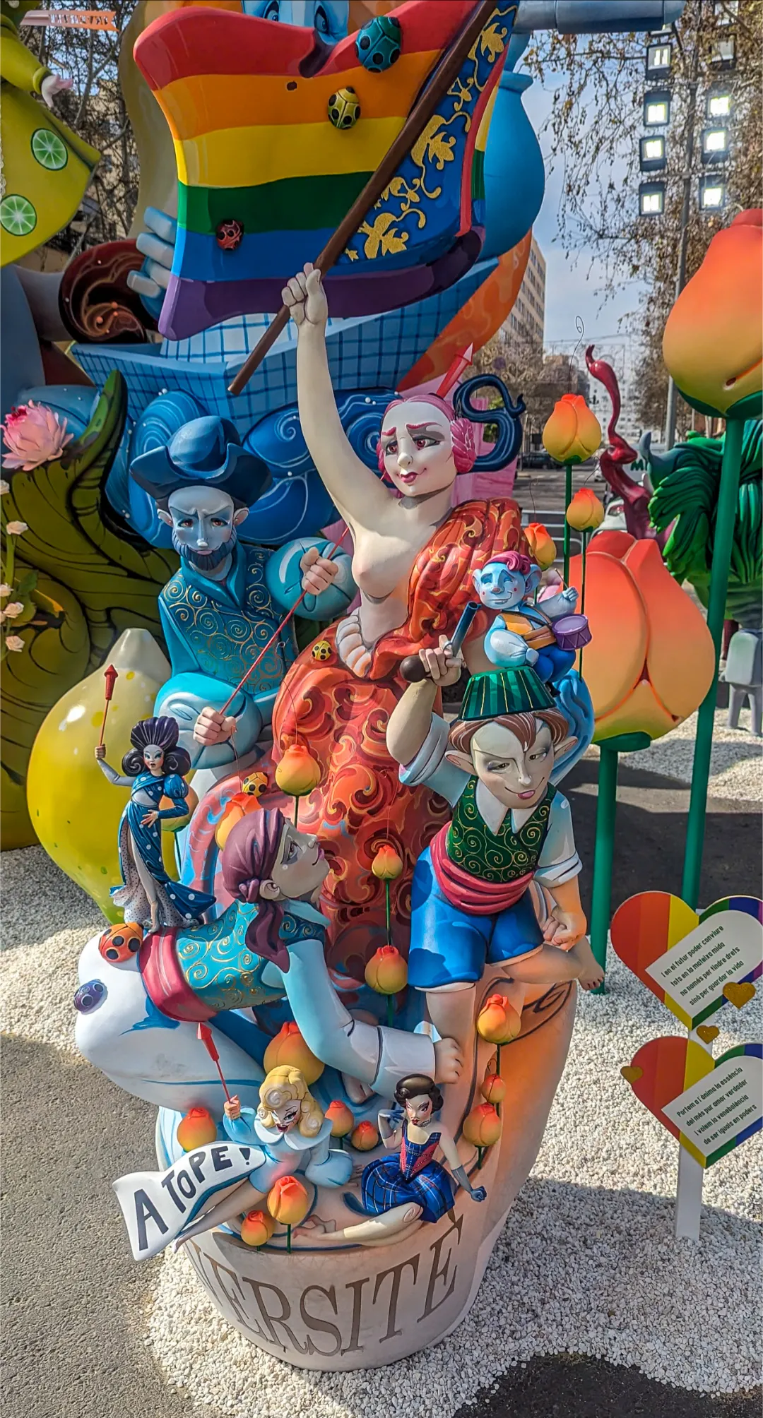 Libertad ondeando la bandera del Orgullo y liderando a un grupo de coloridos personajes hacia adelante.