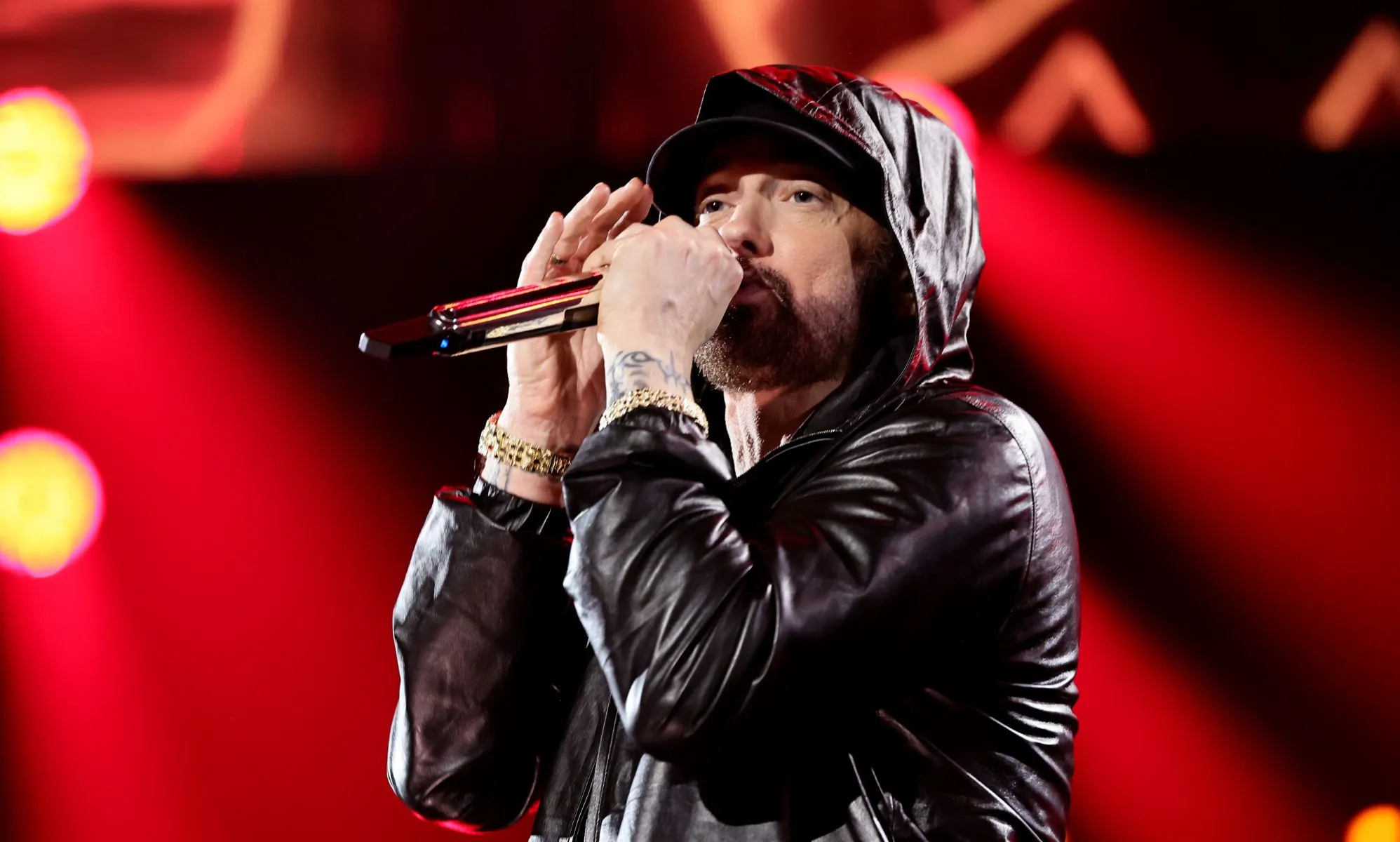 Eminem performing in a black jacket with his hood up.