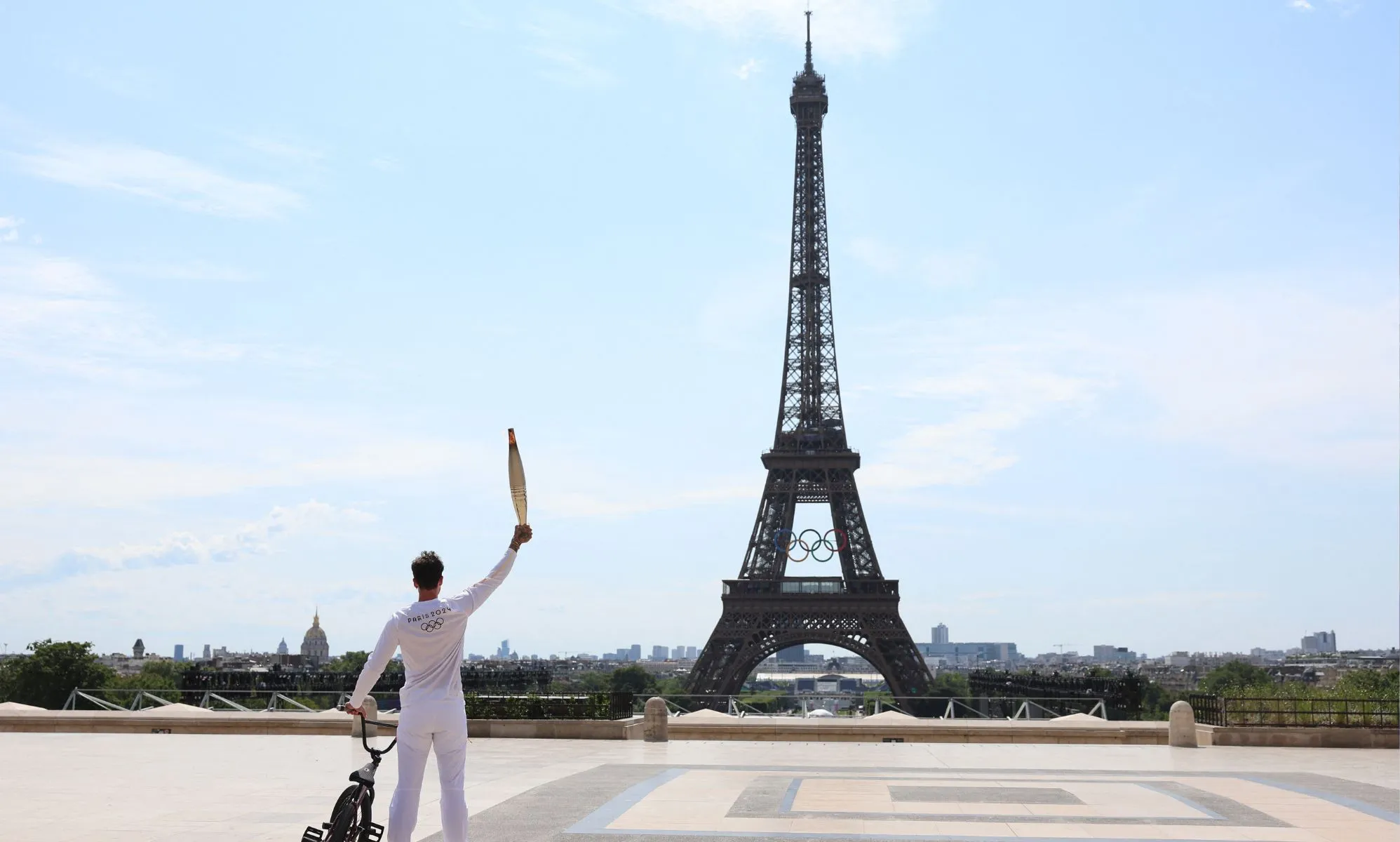 BMX rider posing with the Olympic torch in front of the Eiffel Tower ahead of the Paris Olympics Opening Ceremony