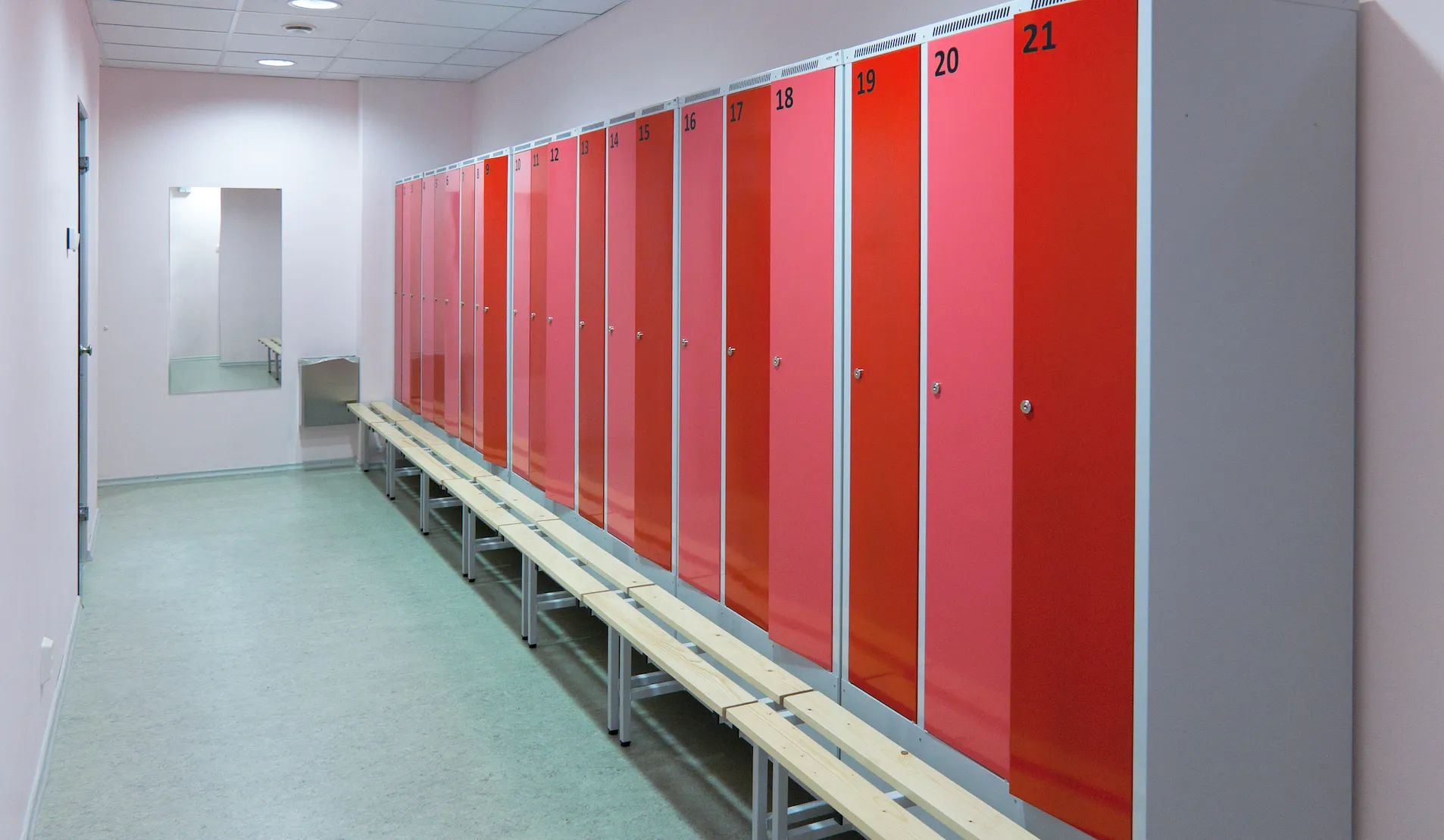A changing room with a row of red lockers