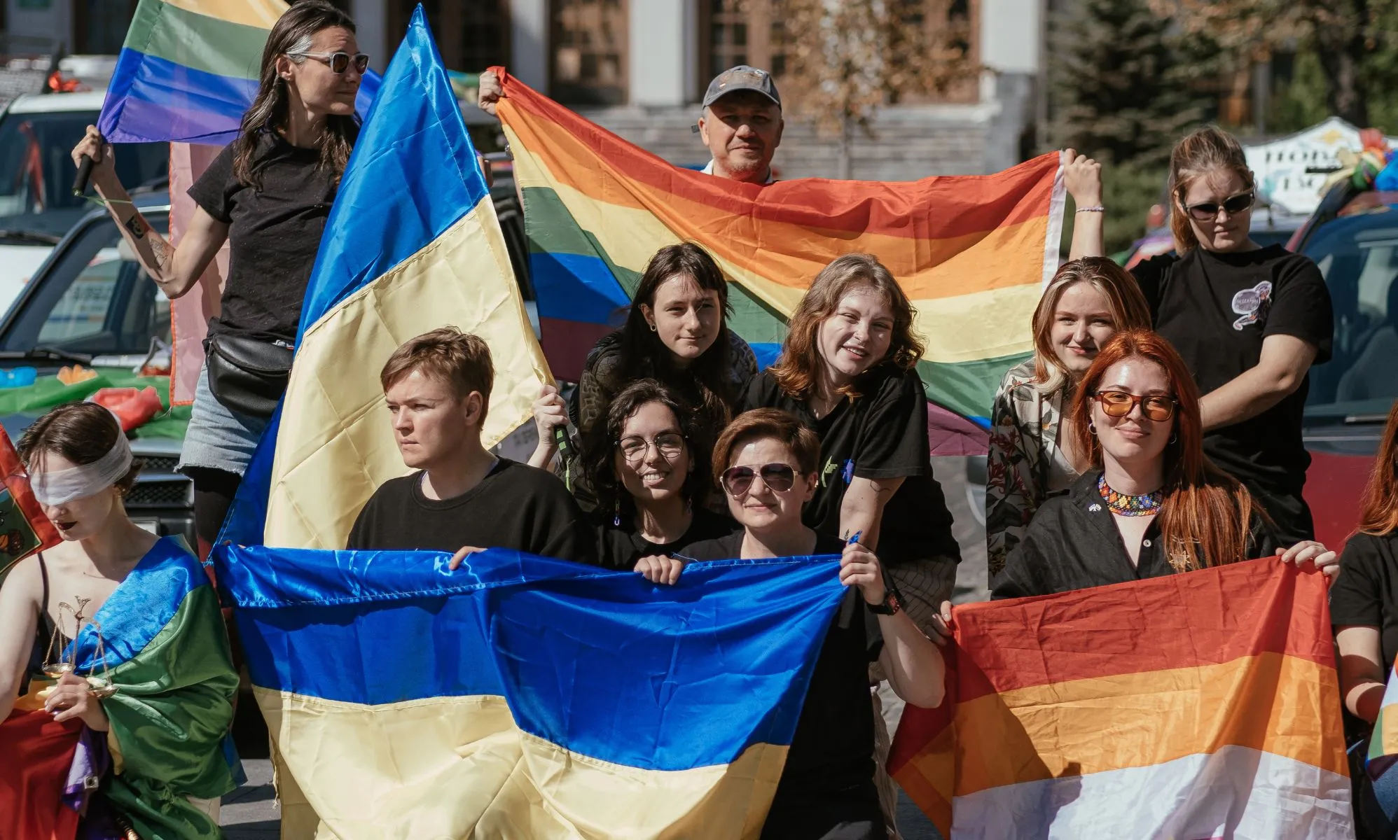 A crowd holding Lesbian, LGBTQ+, and Ukrainian flags.