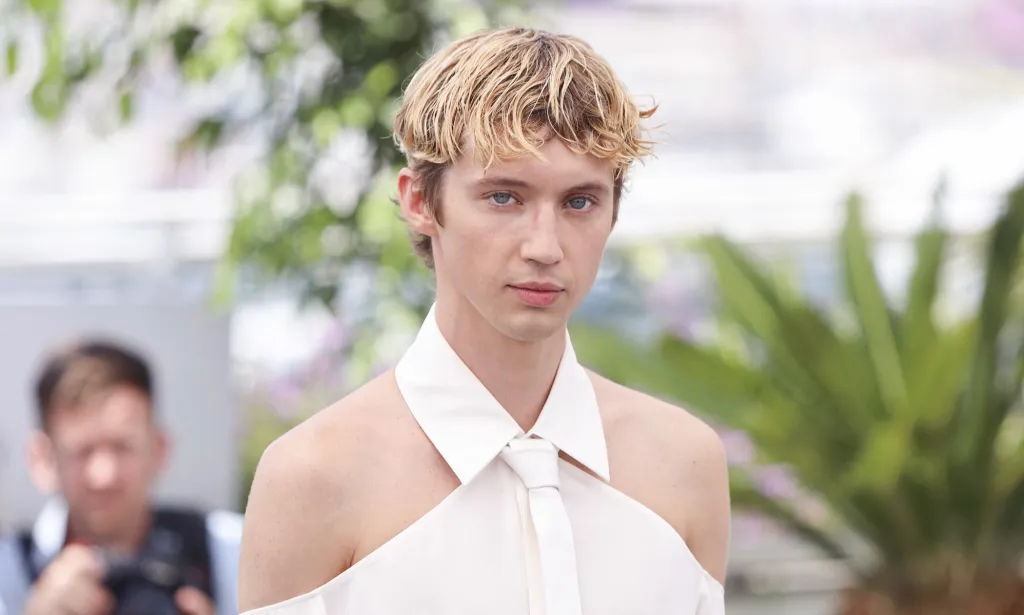Troye Sivan con una camisa blanca sin hombros.