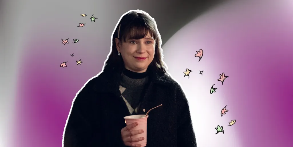 Tori Spring sosteniendo una taza y sonriendo sobre un fondo morado, negro, blanco y gris.