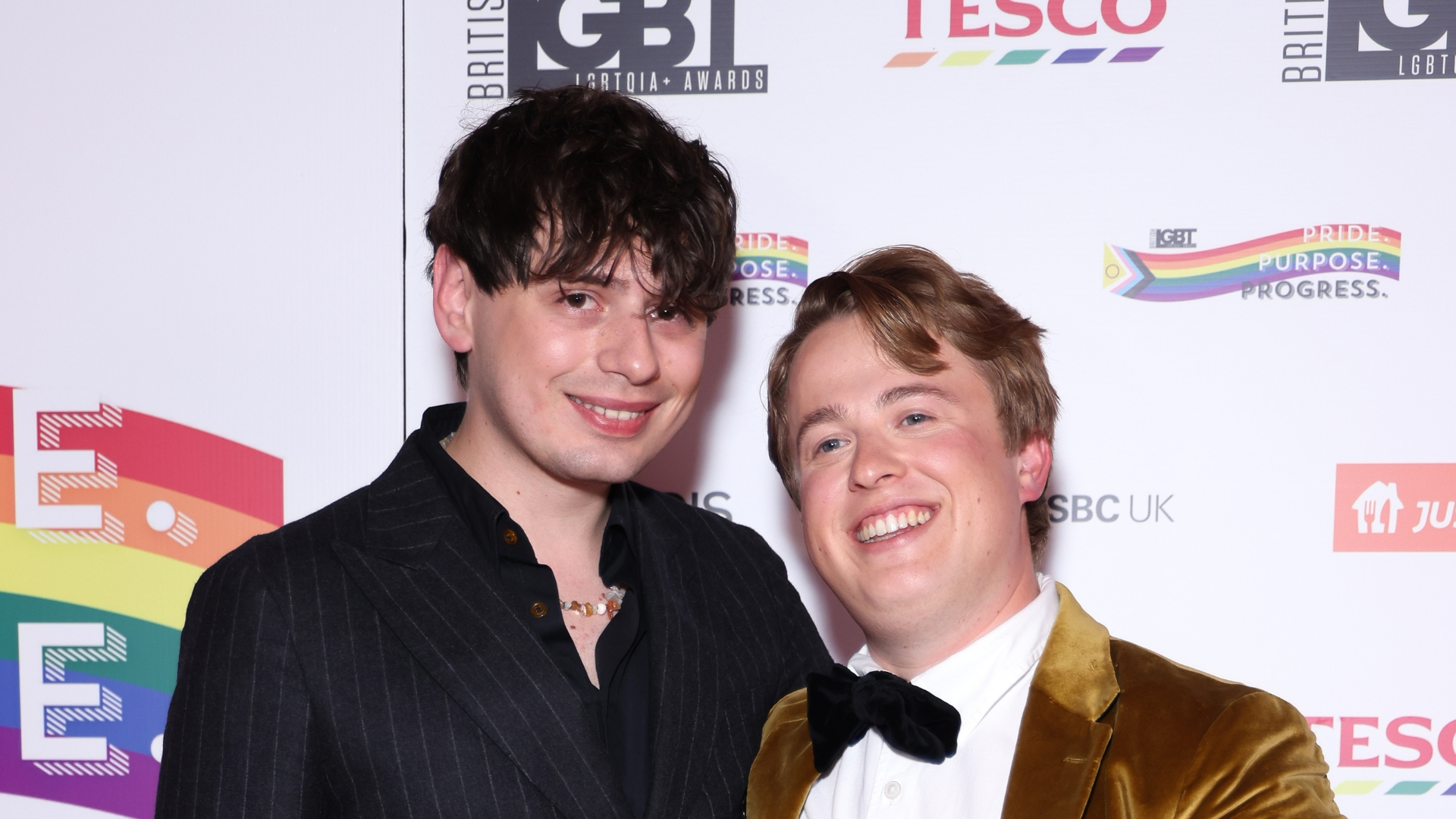 Jordan Sangha and Henry Southan poses with the Media Moment award. Jordan in a dark pinstripe suit and Henry in a gold suit with a black bowtie.