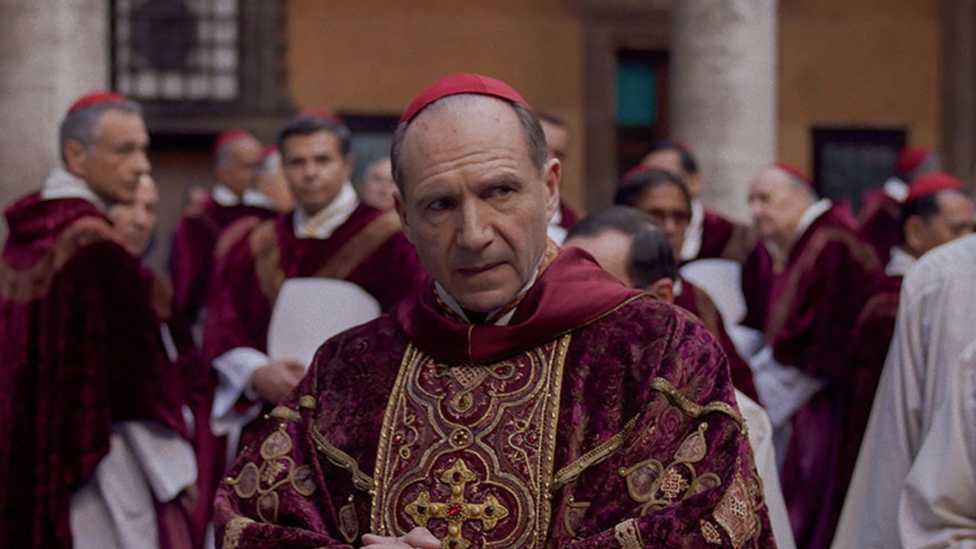 Ralph Fiennes in Conclave as Cardinal Thomas Lawrence in a red and gold robe.