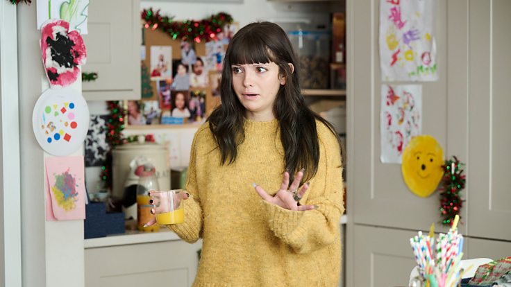 Ramona Márquez como Karen con un jersey amarillo en la cocina.