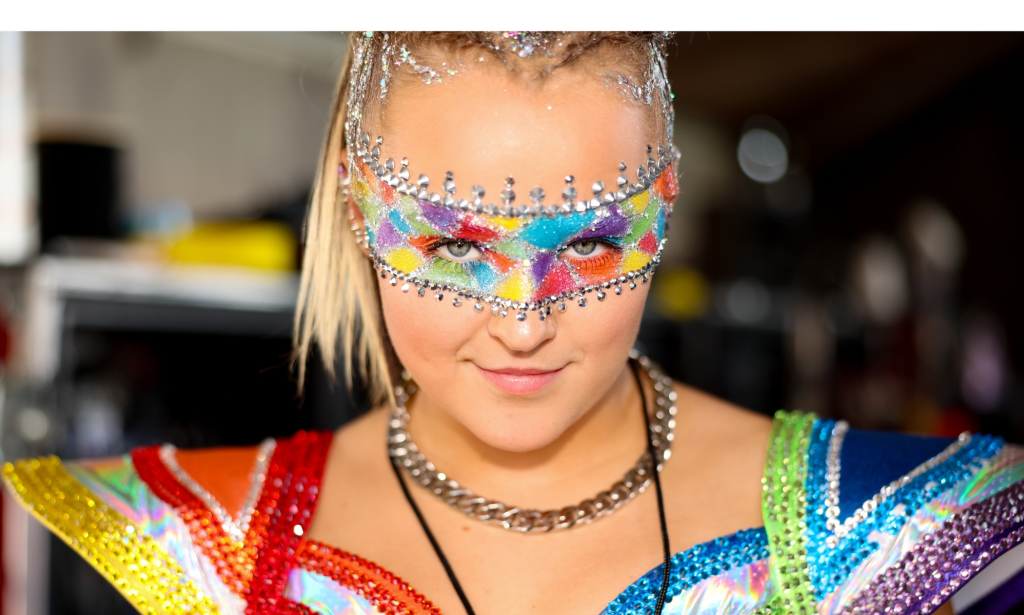 JoJo Siwa se vistió con un traje de concierto de arcoíris y una banda de maquillaje de arcoíris sobre sus ojos.