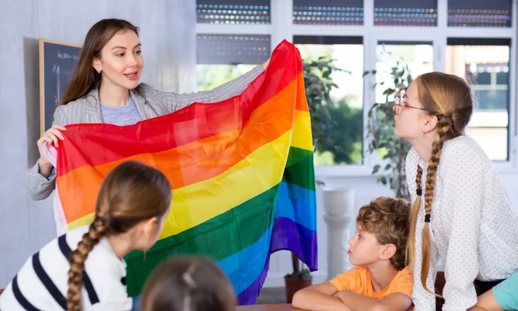 LGBTQ education in action as a teacher shows her class a Pride flag.