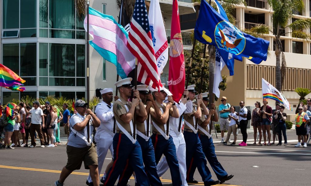 Miembros del Servicio Militar de EE. UU. Con una variedad de banderas, incluida la bandera estadounidense y la bandera trans.