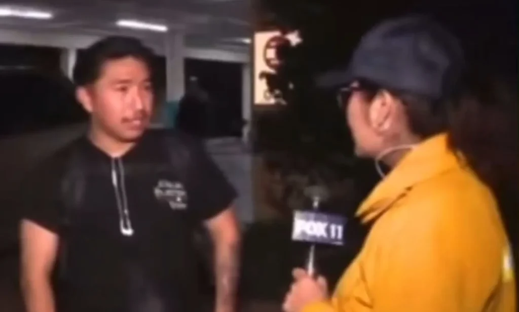 A screenshot of a man speaking to a news reporter in a yellow jacket.