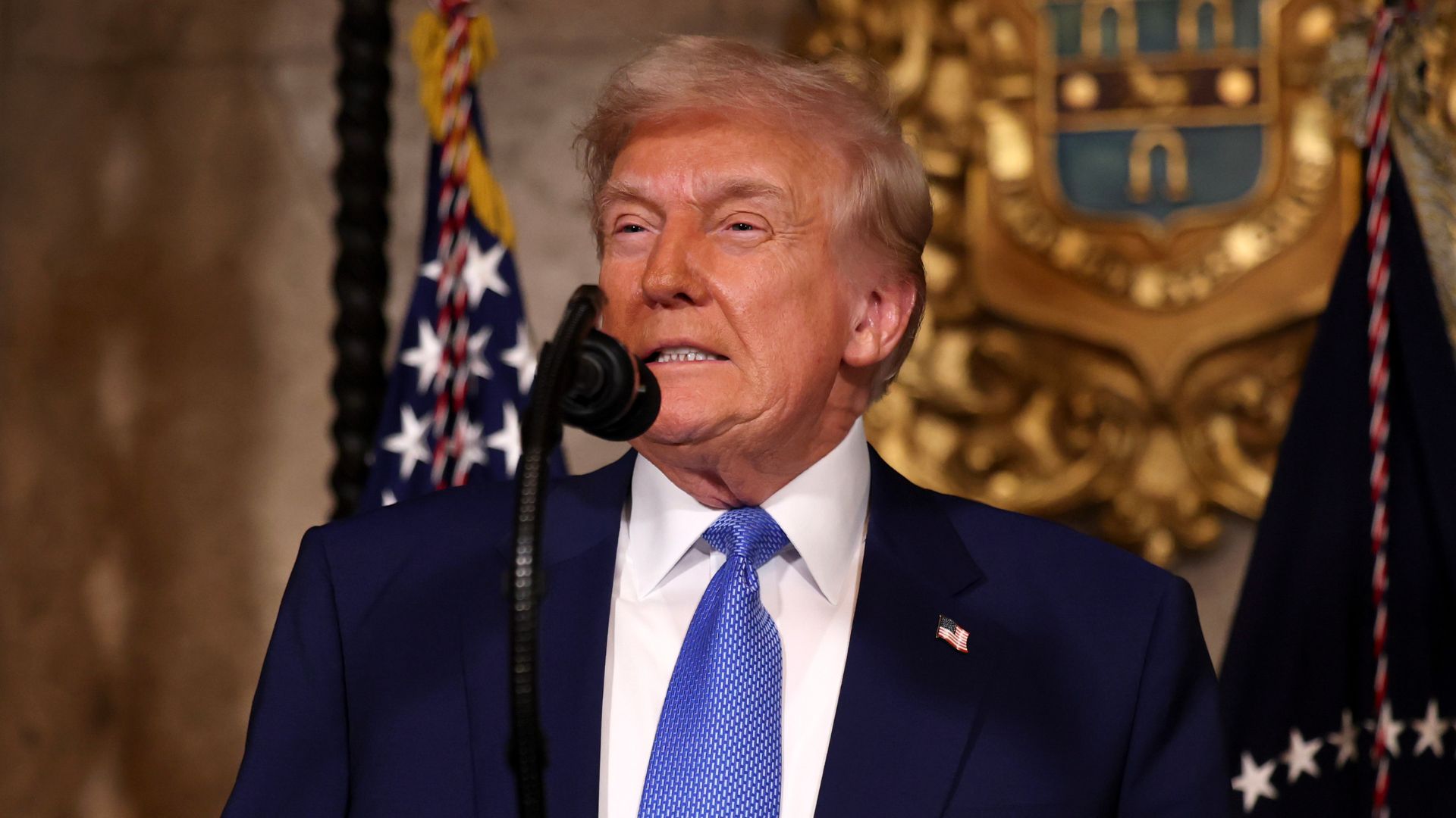 US President Donald Trump stands behind a microphone at a podium