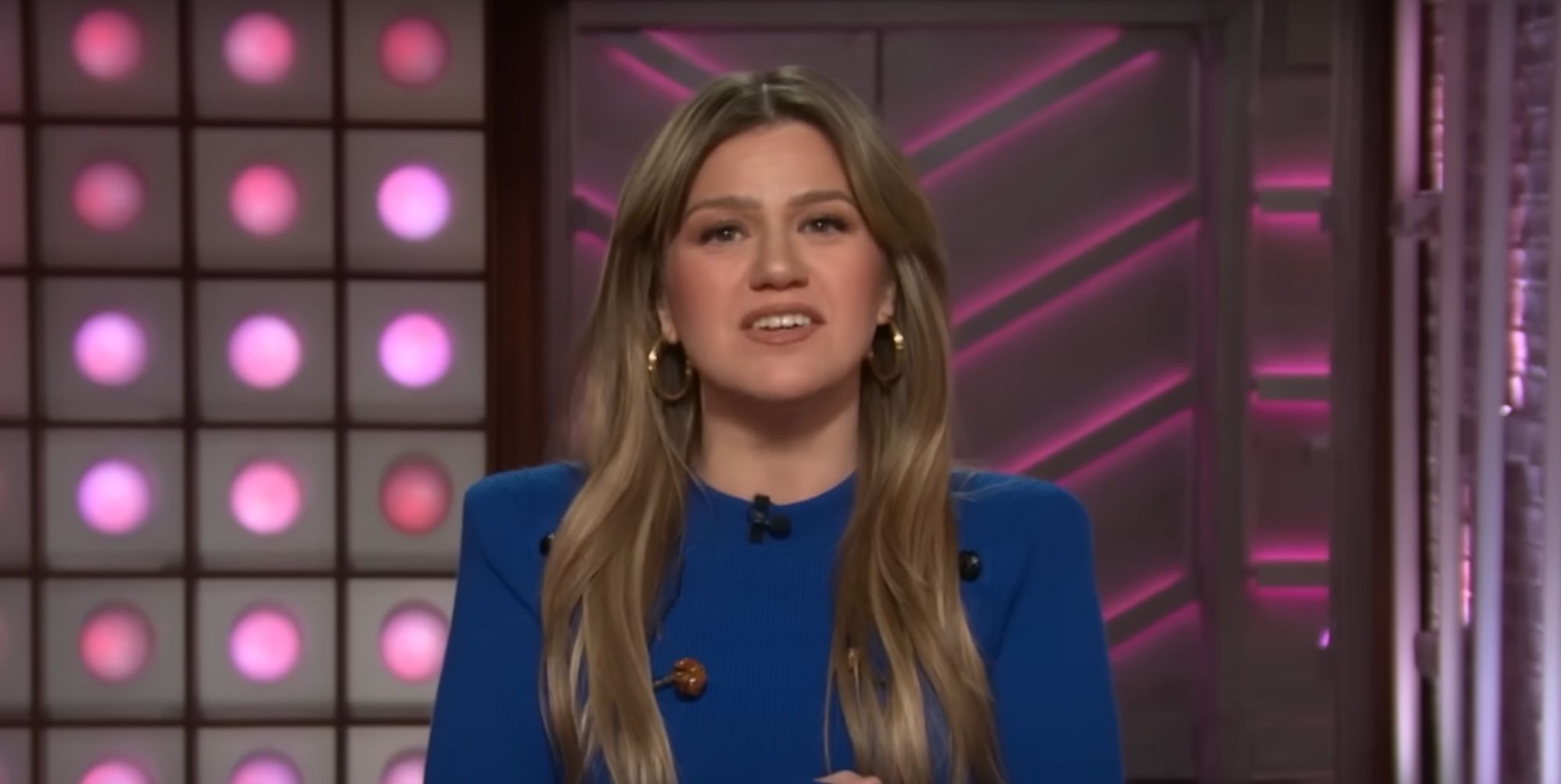 Kelly Clarkson addressing the camera on her talk show, wearing a blue jumper.