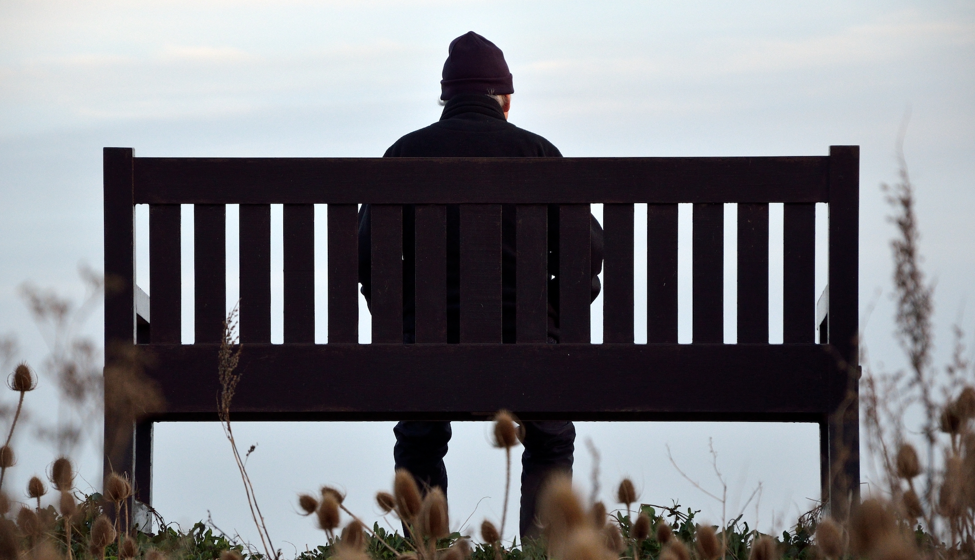 A man sits alone on a park bench.