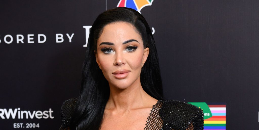 Tulisa poses at a red carpet event while standing against a black and white background.