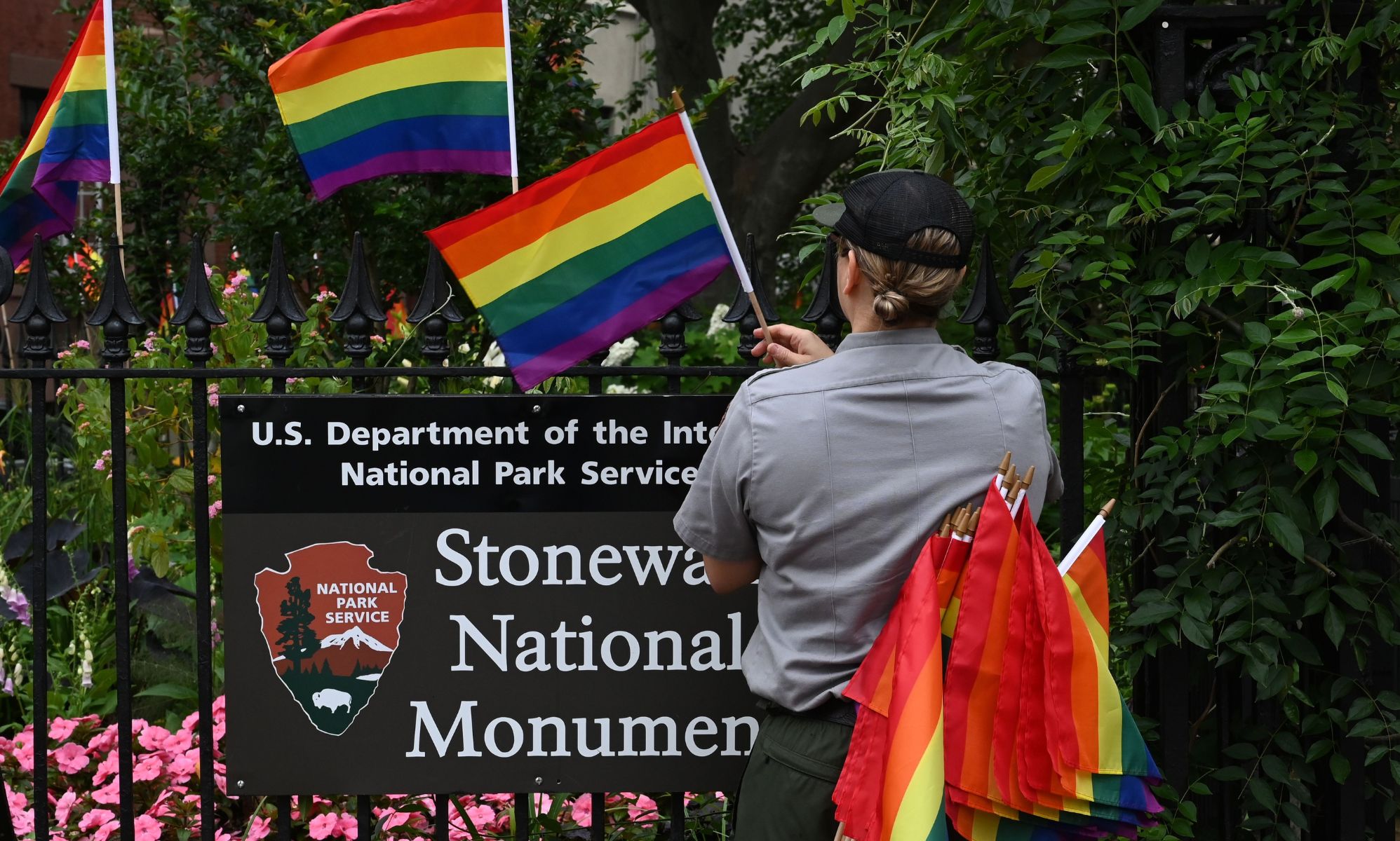 A staff member placing Pride flags on the Stonewall National Monument.