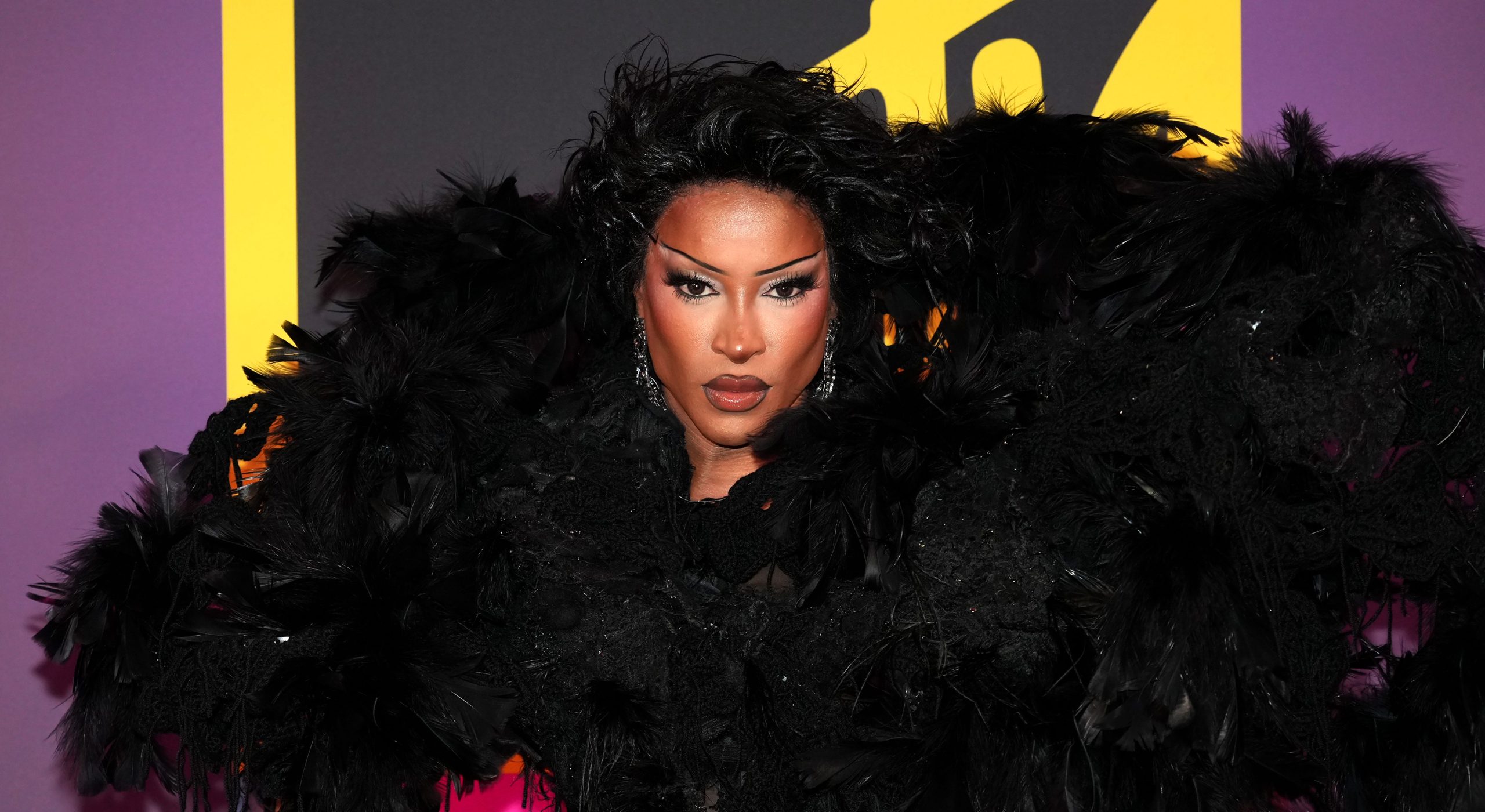 Tayce attends the MTV EMAs 2024. Dressed in a big black feathered shoulder piece.