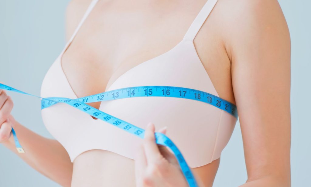 A woman wrapping a tape measure around her chest.