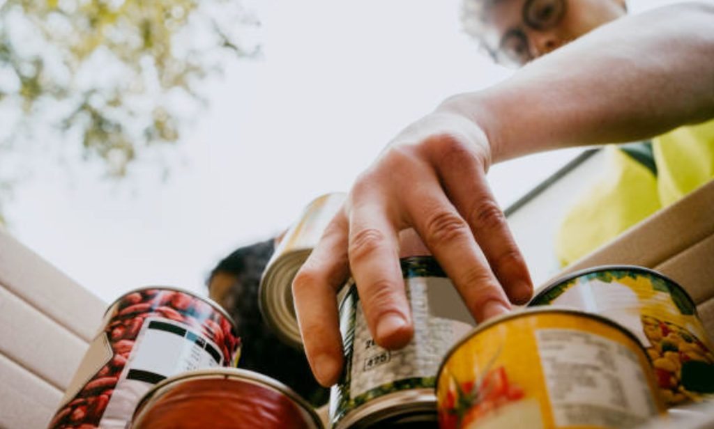 A person stacking tin cans at a food bank.