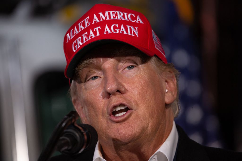 Donald Trump usando una gorra de "hacer que América sea grande nuevamente" mientras habla en un rally.