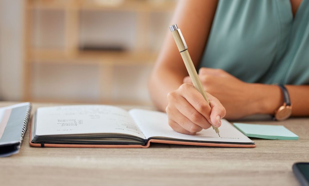 Alguien escribiendo en un libro.
