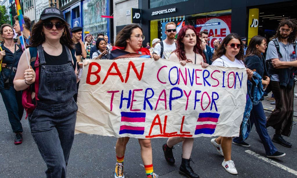 Los activistas tienen un letrero que lee "Ban Therapy de conversión para todos".