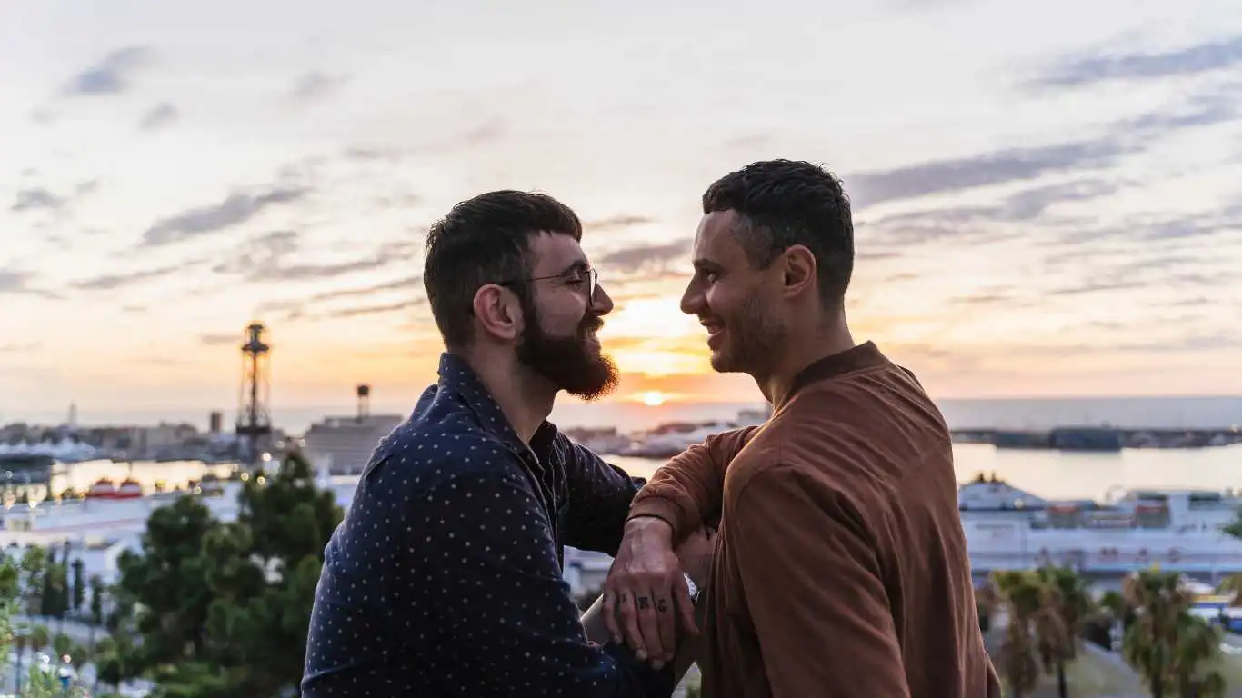 Gay couple on lookout above the city with view to the port, Barcelona, Spain.