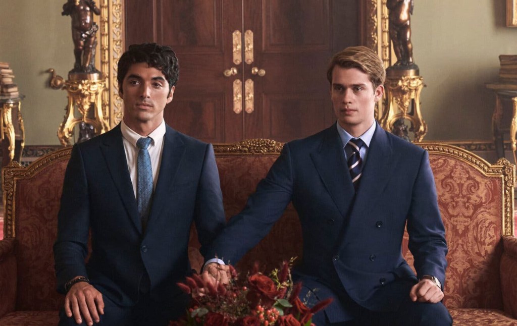 Rojo, blanco y azul real: Alex (Pérez) y el príncipe Enrique (Galitzine) estaban sentados en un sofá rojo y dorado, ambos vestidos con traje. Henry ha estirado el brazo para tomar la mano de Alex.