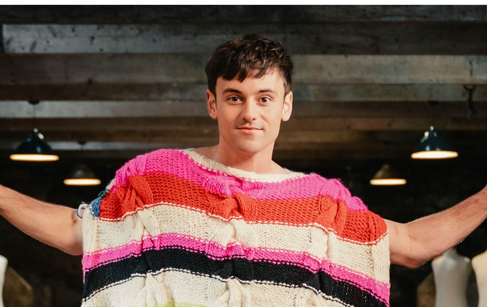 Tom Daley is the host of Game of Wool: Britain’s Best Knitter. Standing with a brightly knitted poncho