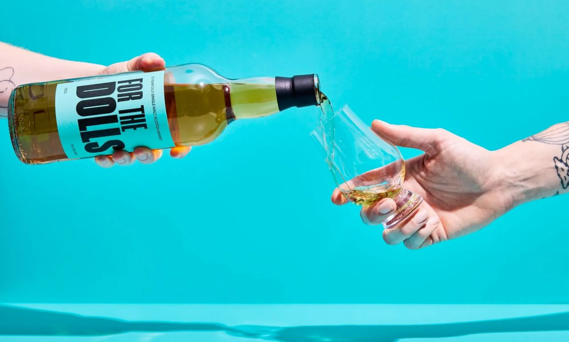 An unpictured person pouring a bottle of the For the Dolls whisky.