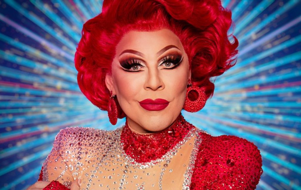 La Voix in all red in front of a blue strictly background