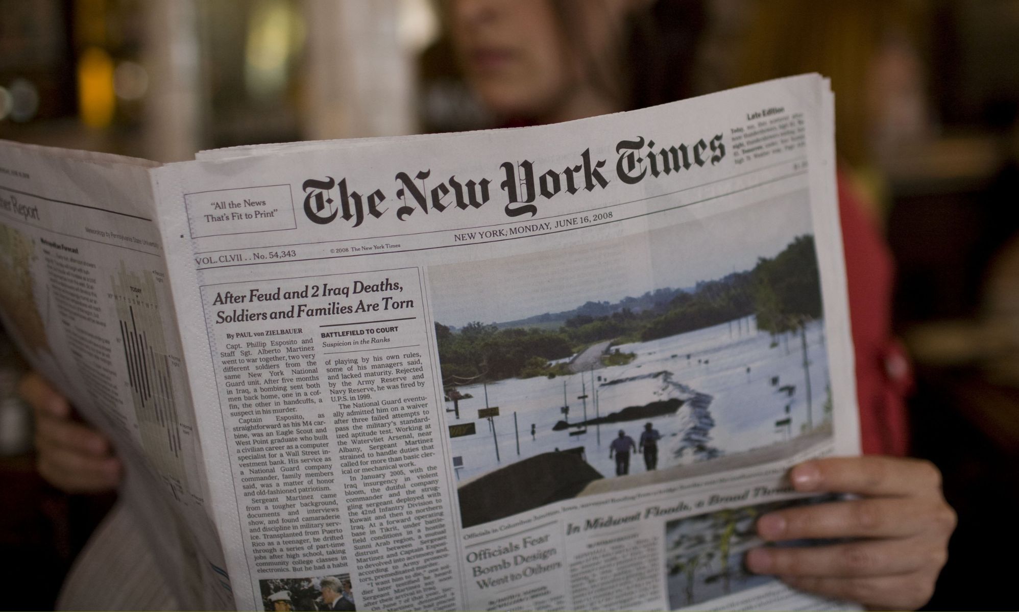 A person holding a copy of the New York Times paper.