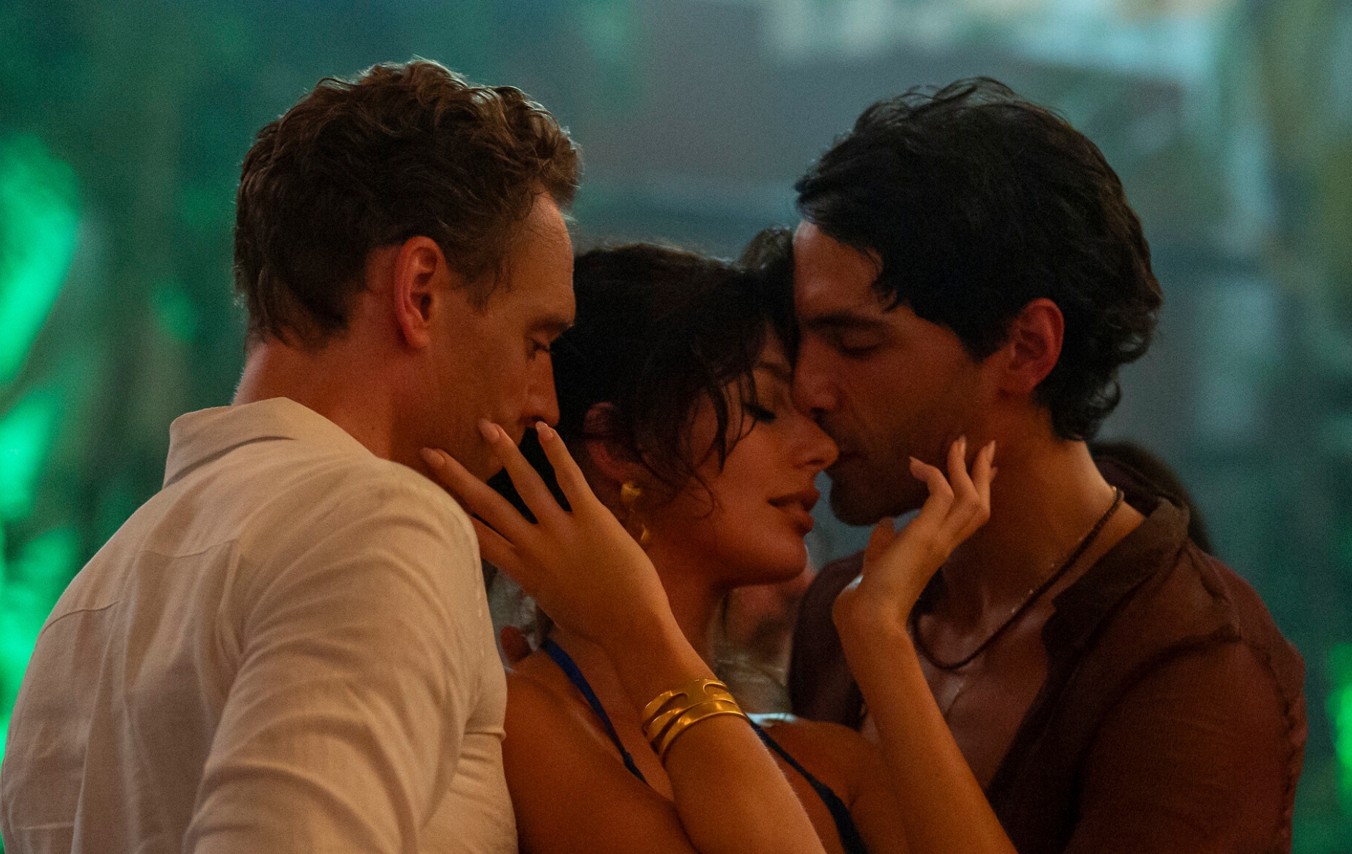 The Night Manager still: Tom Hiddleston as Jonathan Pine, Camila Morrone as Roxana and Diego Calva as Teddy. The three pressed close together dancing