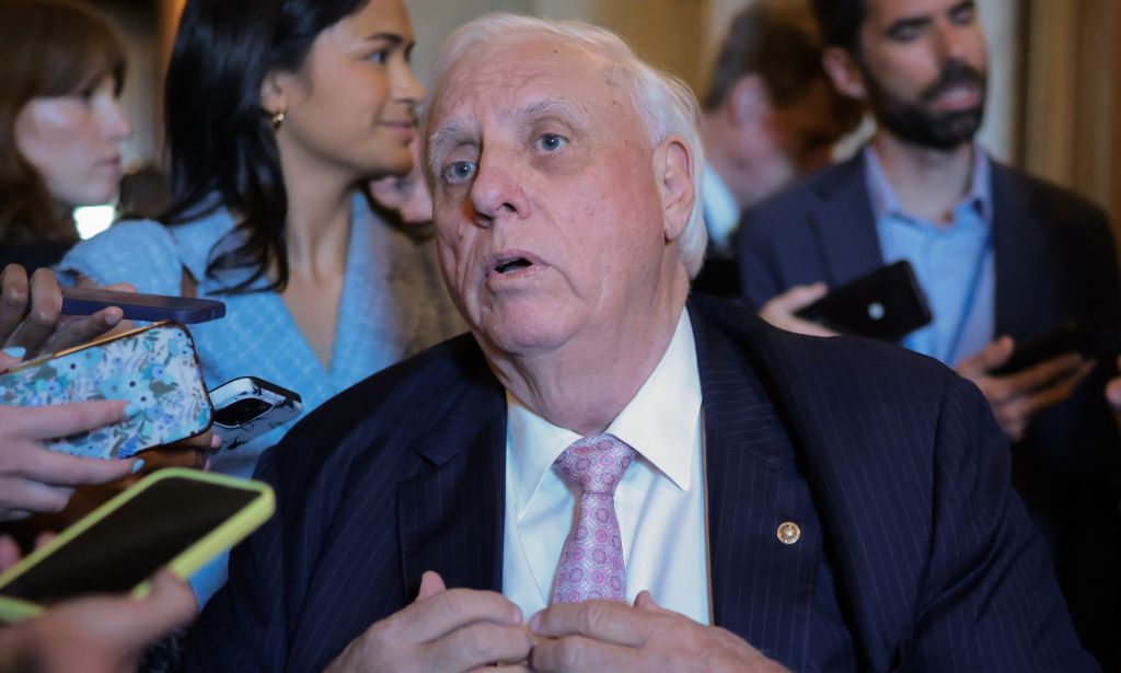 Jim Justice rodeado de prensa sosteniendo teléfonos, que utilizan como micrófonos.