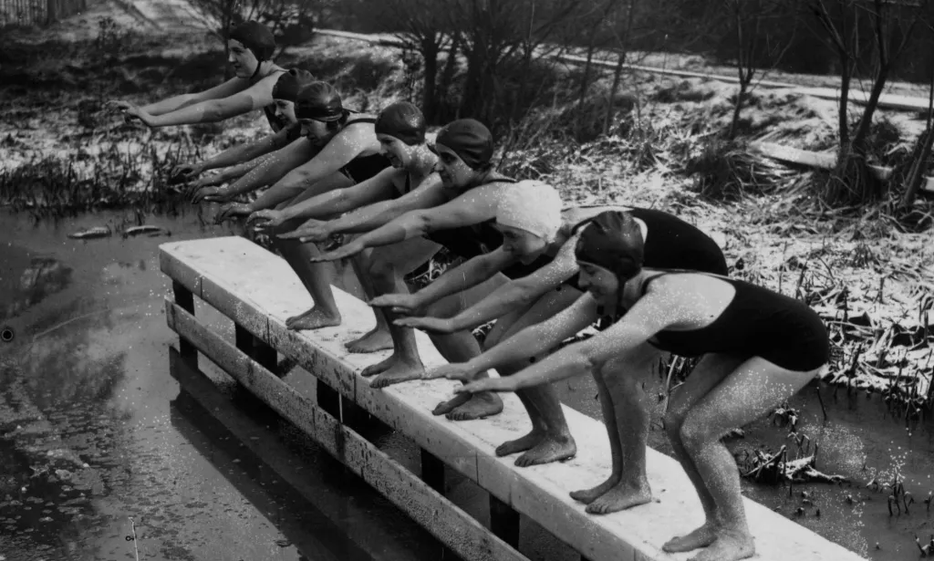 Una fotografía de 1935 de mujeres cubiertas de nieve preparándose para sumergirse en la piscina para mujeres Kenwood.