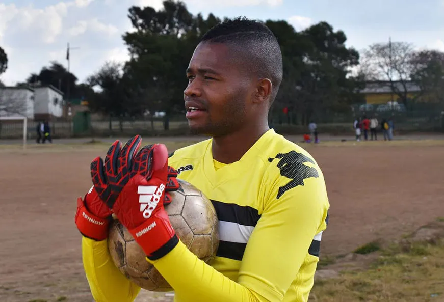 El futbolista sudafricano gay Phuti Lekoloane sostiene una pelota de fútbol