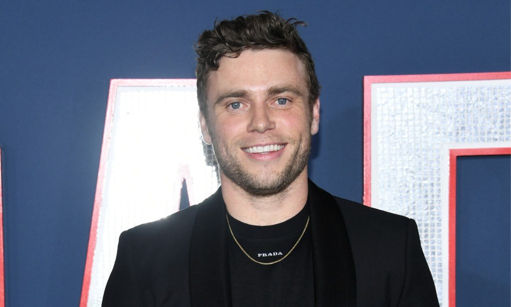 Photo of actor Gus Kenworthy wearing a black suit at the 80 for brady premiere