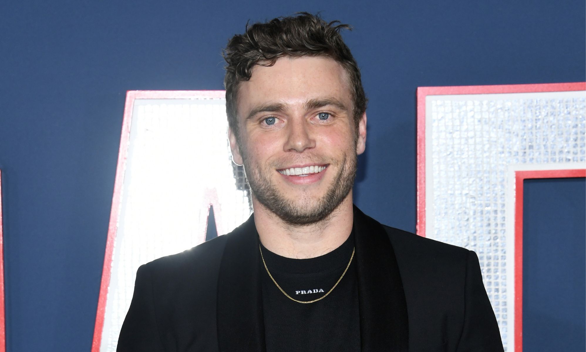 Photo of actor Gus Kenworthy wearing a black suit at the 80 for brady premiere