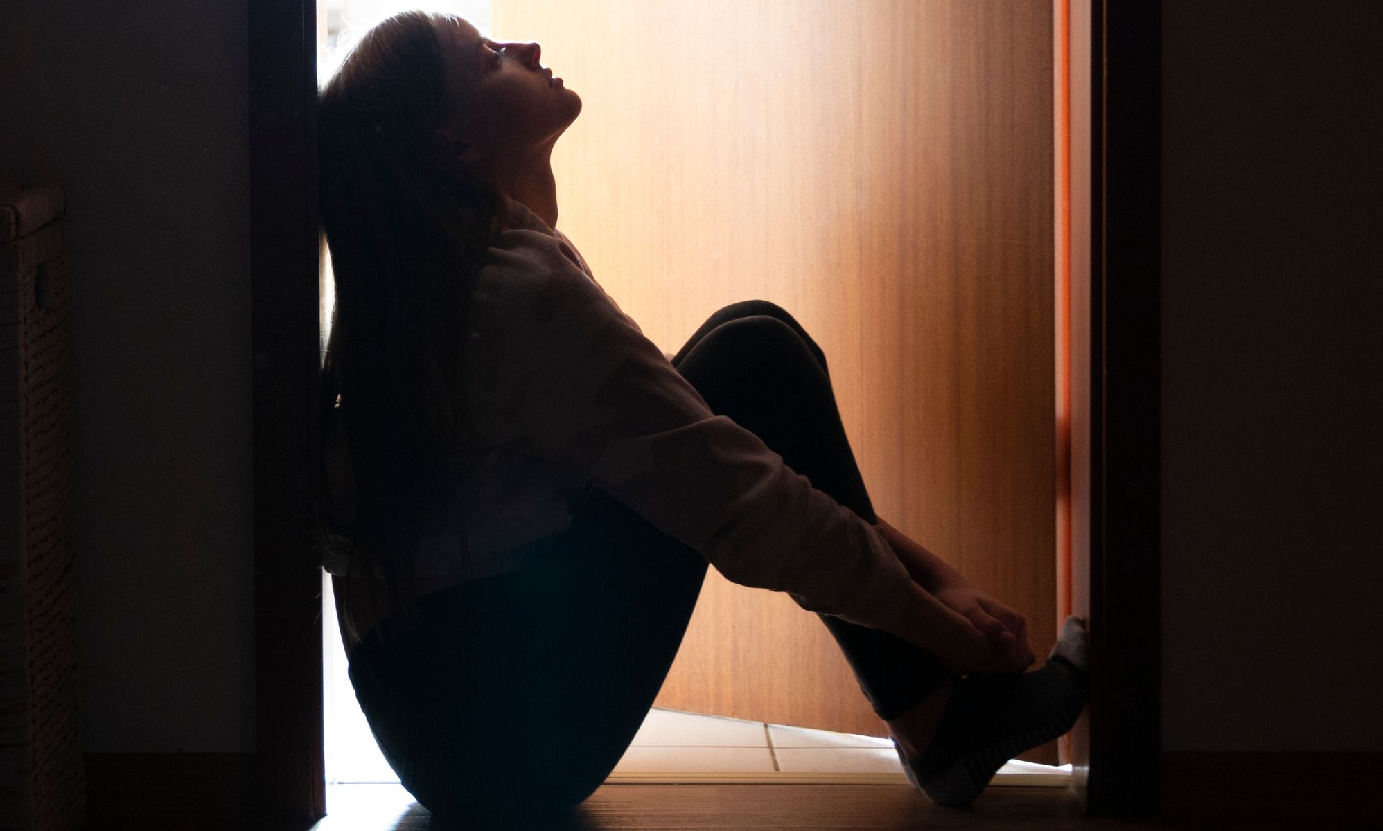 A young person sat pensively in a doorway.