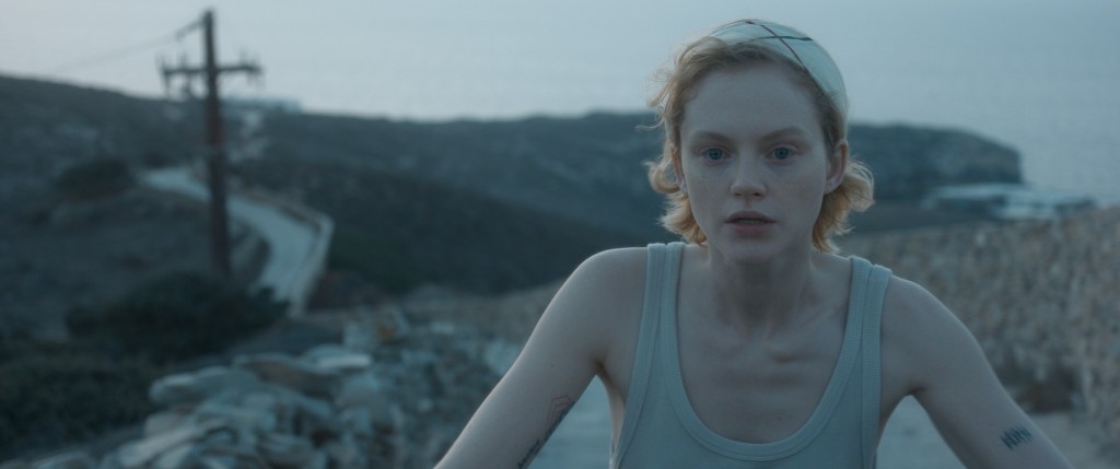 Imagen de satisfacción de Emma Laird en bicicleta por un camino de tierra con un chaleco gris