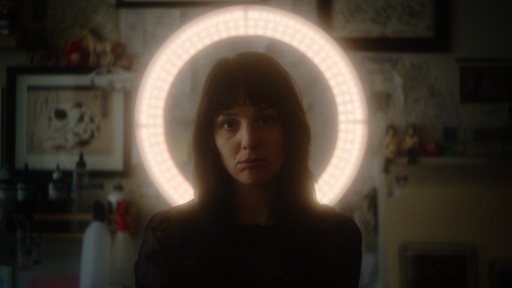 una persona con silueta parada frente a un foco de halo en un estudio de tatuajes