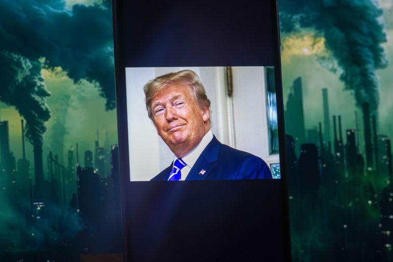 La pantalla de un teléfono inteligente muestra una foto del presidente Donald Trump, con las chimeneas de una fábrica humeante que ilustra el impacto en el medio ambiente global.