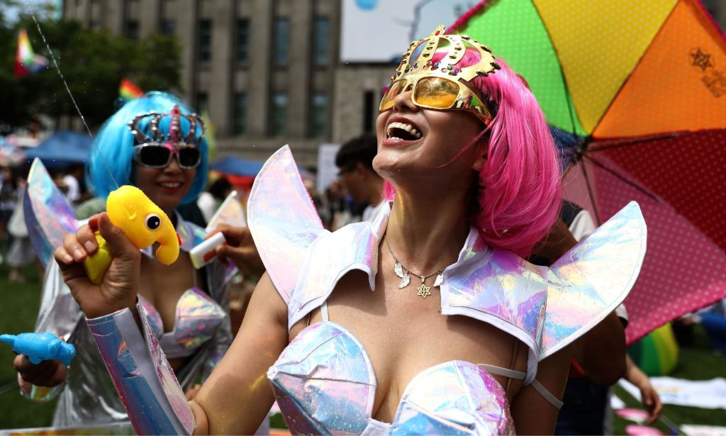 Una persona vestida de Orgullo usando una pistola de agua.