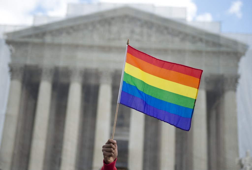 Un partidario del matrimonio entre personas del mismo sexo ondea una bandera arcoíris frente a la Corte Suprema de Estados Unidos.