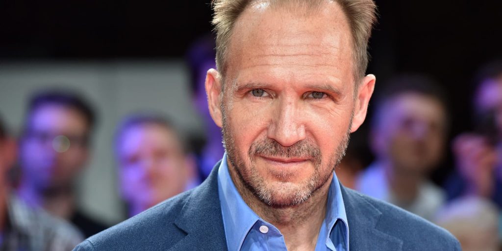 Headshot of Ralph Fiennes wearing a blue shirt and blazer