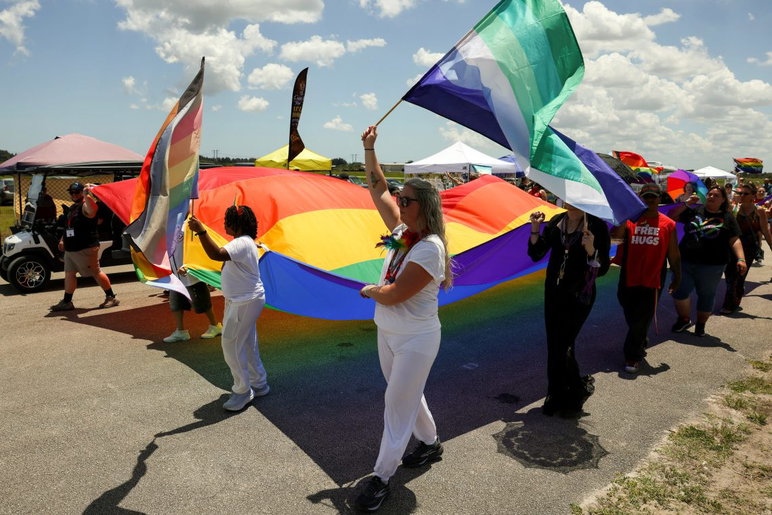 La gente porta una gran bandera del arco iris mientras marcha en el desfile durante el quinto festival anual del Orgullo de la Costa del Tesoro el 25 de abril de 2026, en el recinto ferial del condado de St. Lucie. El evento fue organizado por el Santuario de la Costa del Tesoro.