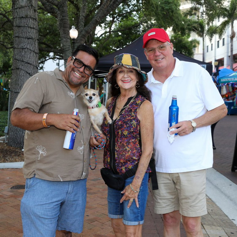 Luis Ayala y su esposo (derecha), su perra Perdita y su amiga Suzanne Stacy (centro) disfrutan del festival callejero y toman una cerveza.