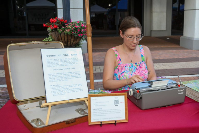 ¡La poeta viva es Nora Long y mira su máquina de escribir antigua! ¡No se necesita White-Out ya que los dedos de este poeta vuelan sobre las teclas con palabras proporcionadas por usted!