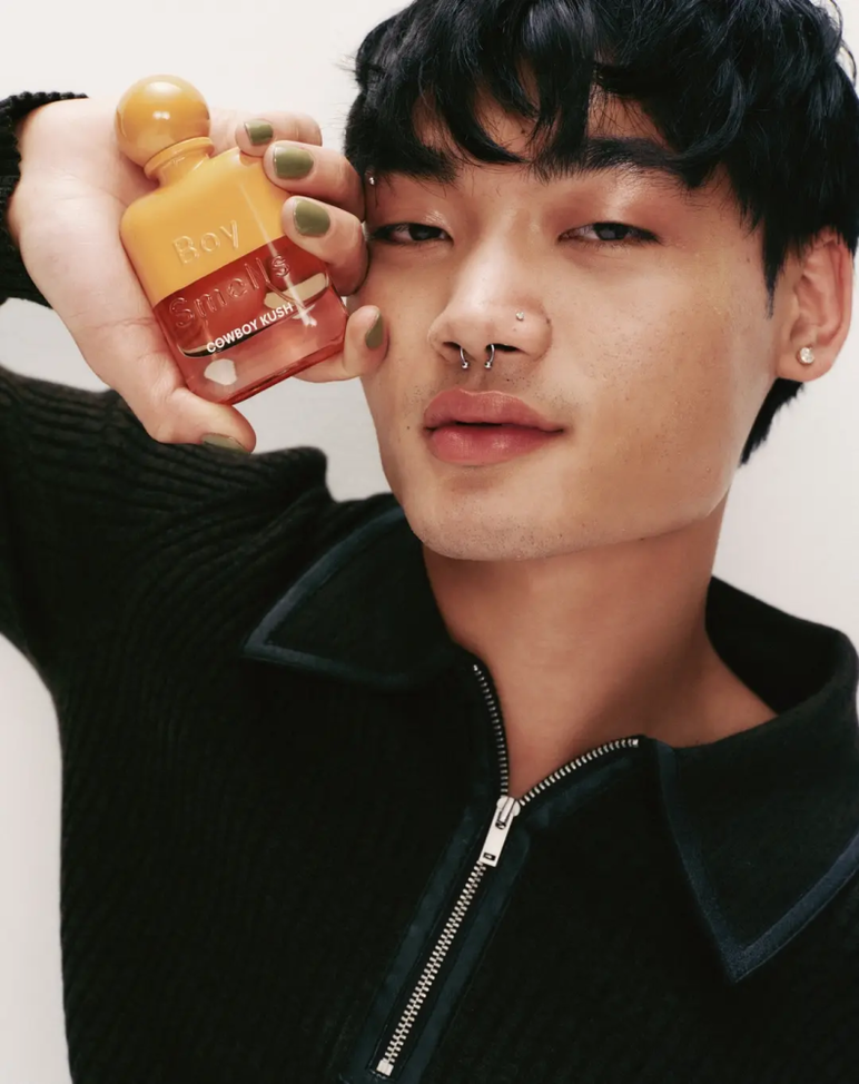 un modelo sosteniendo una botella de aroma Boy Smells Cowboy Kush