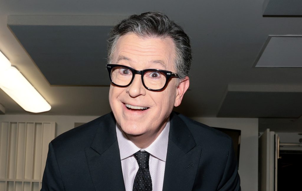 Stephen Colbert smiling at the camera in a suit